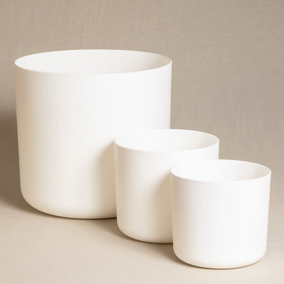 Drei weiße, zylindrische Topfsets aus Keramik (30, 18, 16) unterschiedlicher Größe sind minimalistisch vor einem neutralen Hintergrund arrangiert. Der größte Topf steht hinten, die beiden kleineren Topfsets (30, 18, 16) sind davor und etwas seitlich davon platziert.